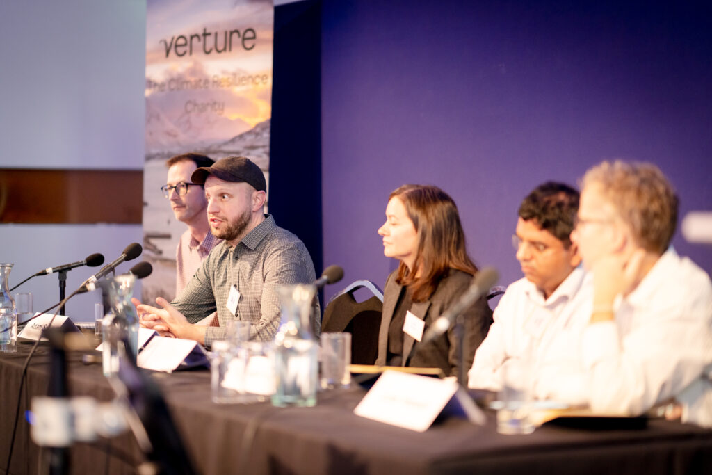 Five MACC Hub members take part in a panel discussion on stage, leading the conversation from the front of the room.
