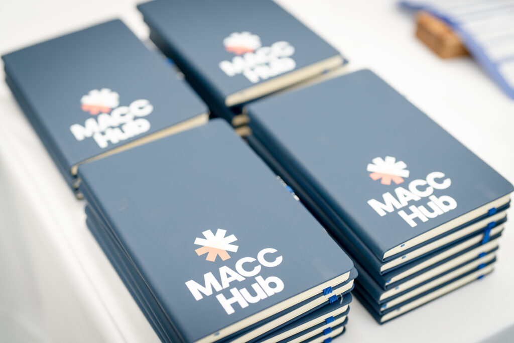 MACC Hub branded notebooks and pens arranged on a table.
