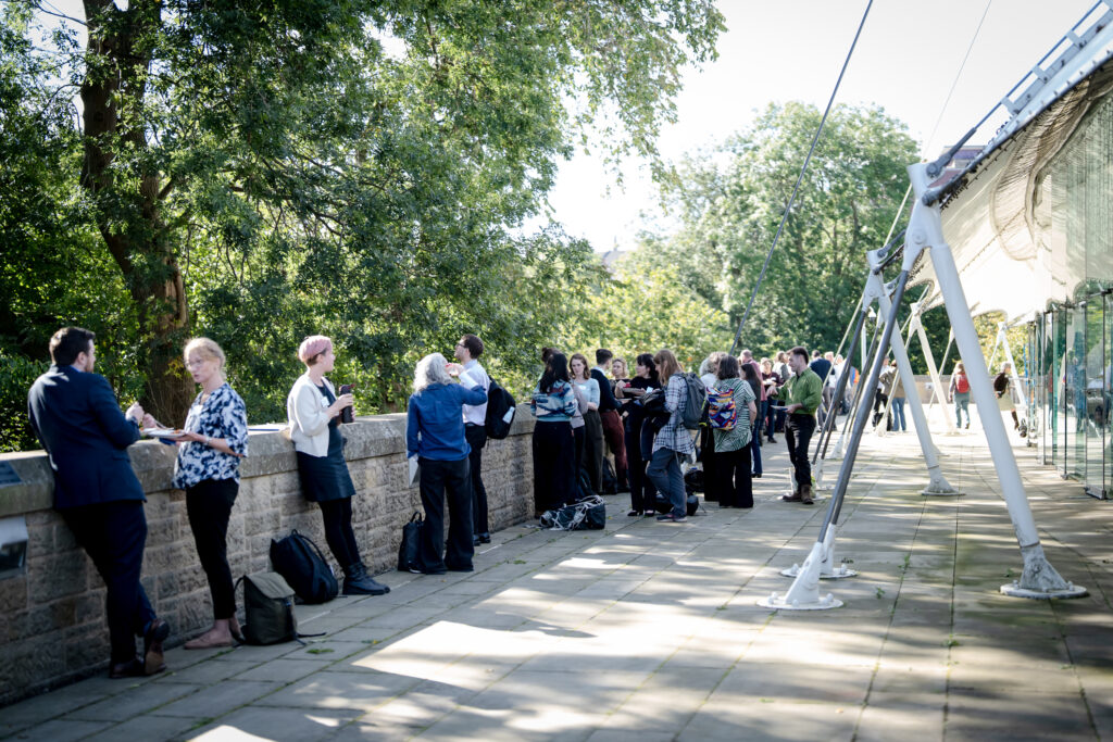 Delegates networking and chatting outside the venue during a coffee break at the MACC Hub conference.
